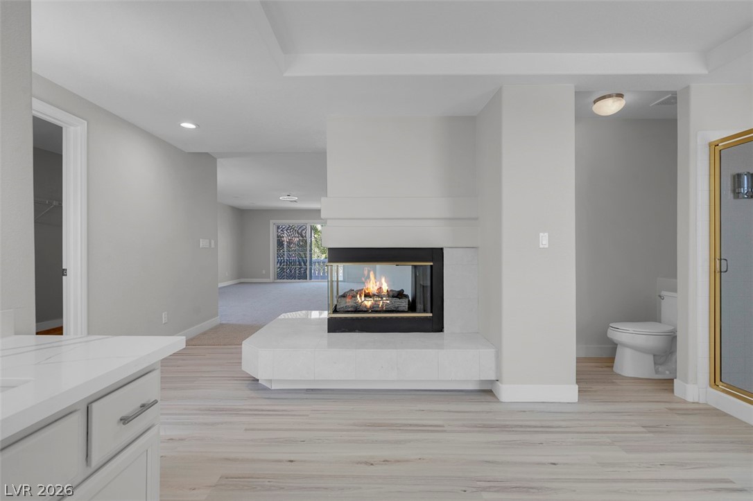 3604 North Campbell Road Las Vegas, NV 89129 - Photo 38 of 54 Living area with a multi sided fireplace, baseboards, light wood-style floors, and recessed lighting