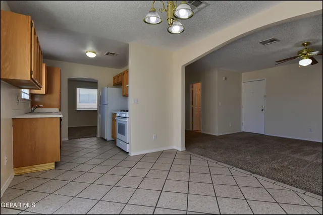 an empty room with a chandelier fan and windows