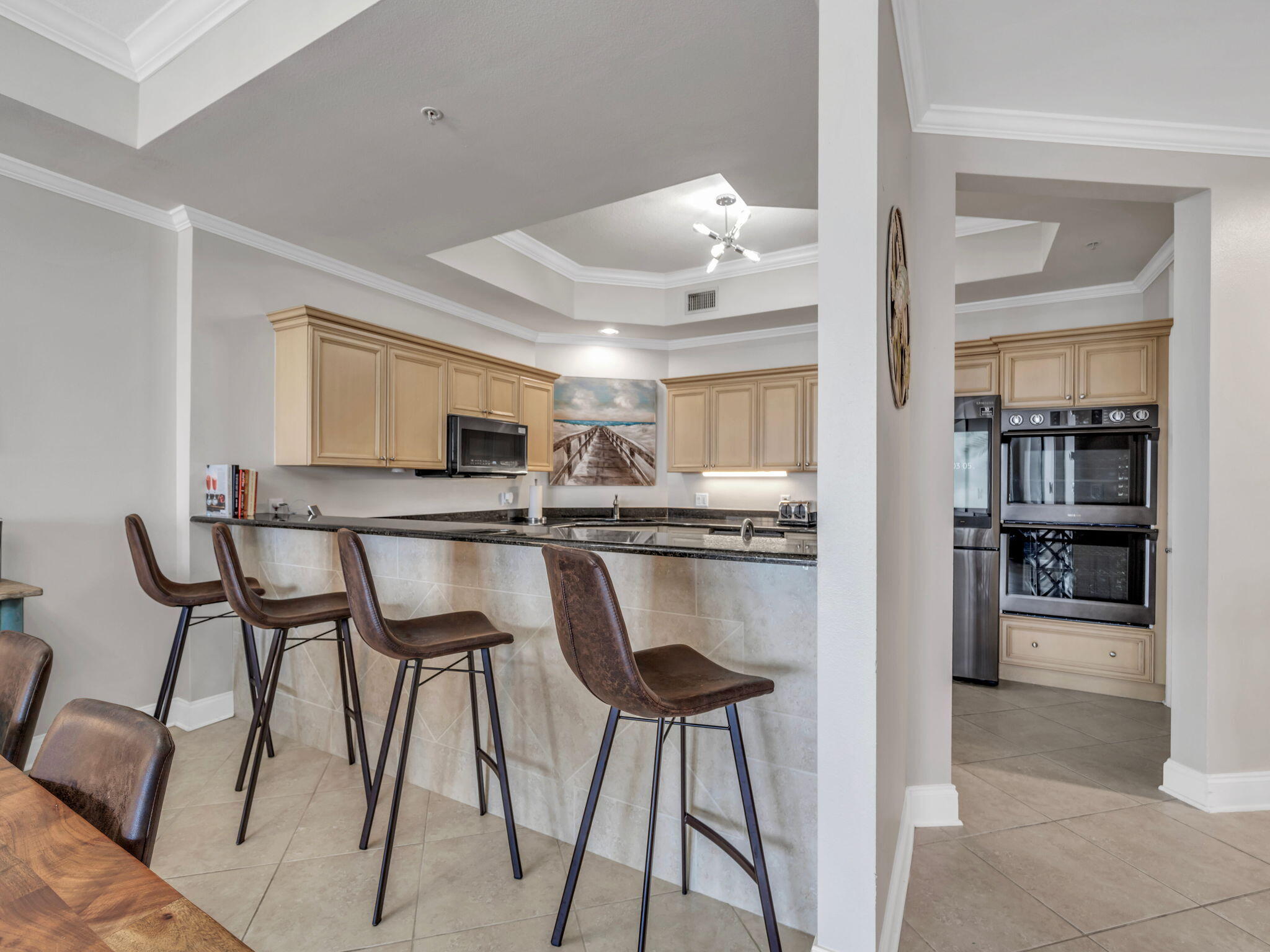 5 Calhoun Avenue, Unit 403 Destin, FL 32541 - Photo 9 of 35 a kitchen with stainless steel appliances kitchen island granite countertop a table chairs sink and cabinets
