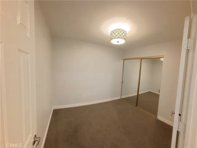 an empty room with closet and a chandelier fan