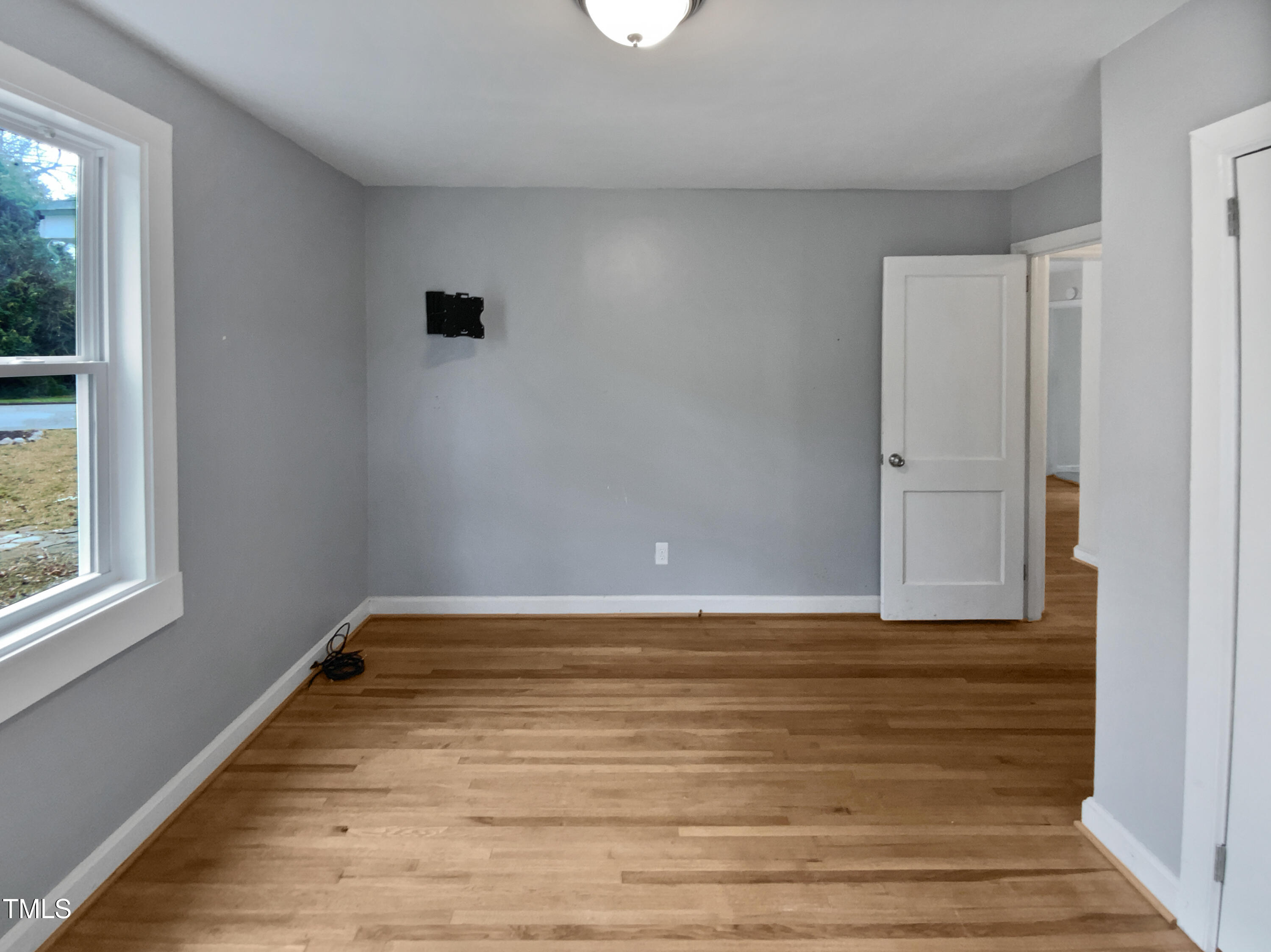 802 Powell Drive Garner, NC 27529 - Photo 14 of 17 a view of an empty room with wooden floor and a window