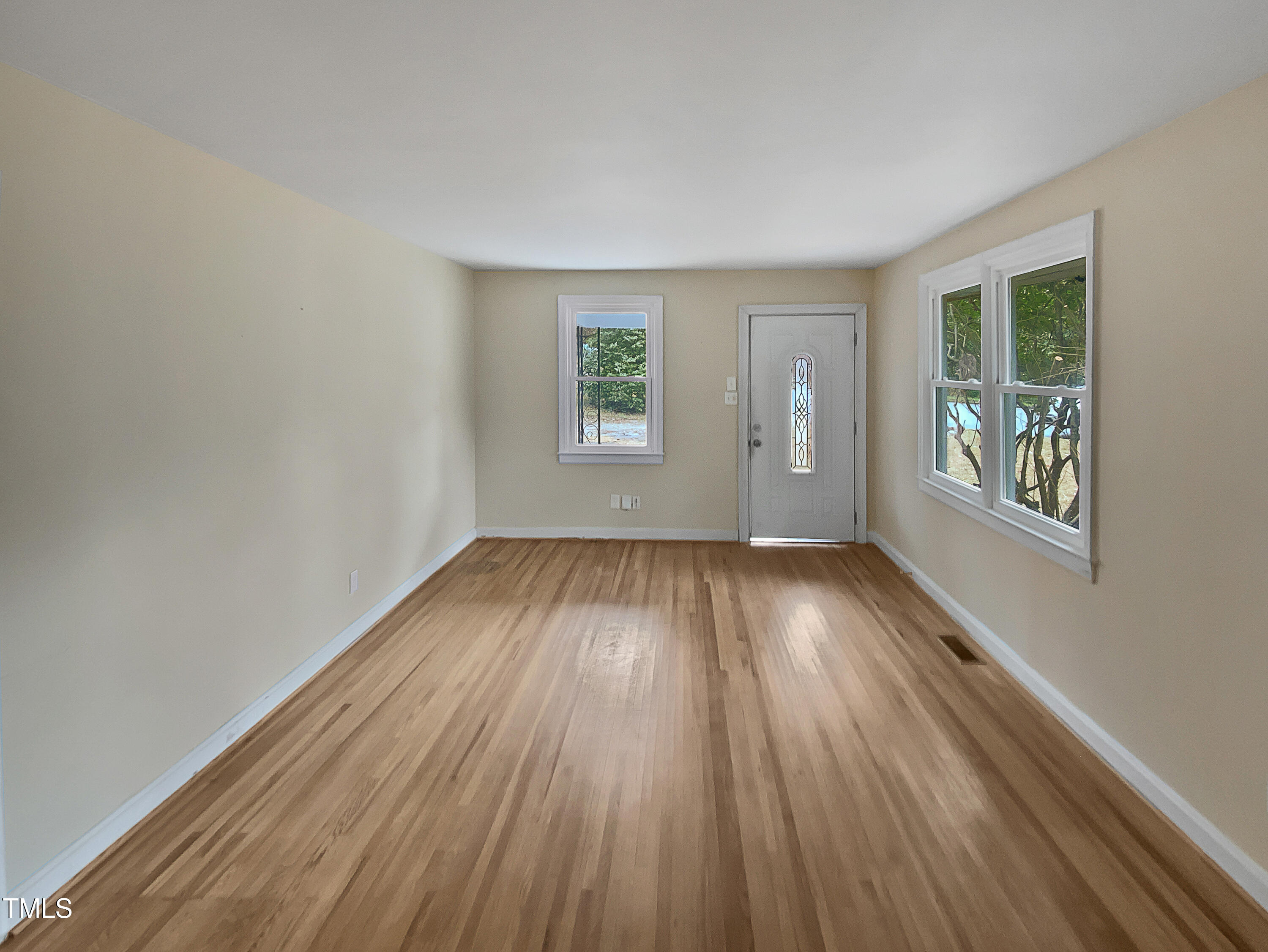 802 Powell Drive Garner, NC 27529 - Photo 3 of 17 an empty room with wooden floor and windows