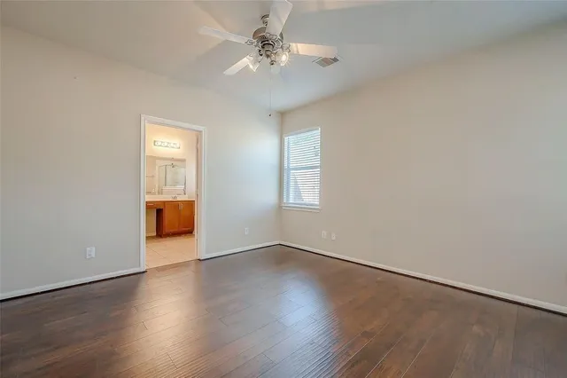 an empty room with wooden floor closet and windows