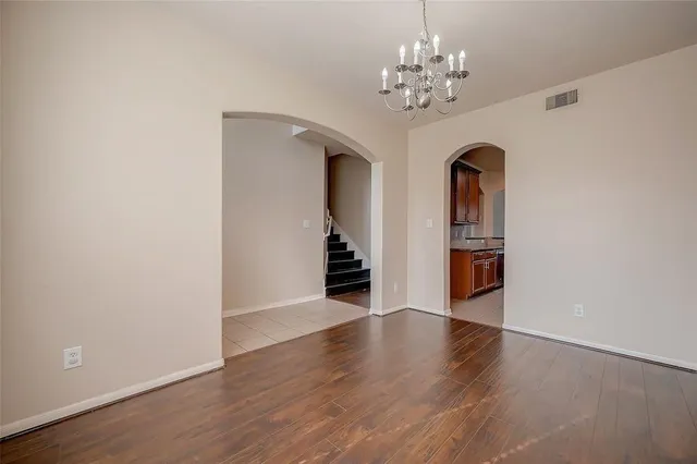 a view of a hallway with wooden floor and a chandelier