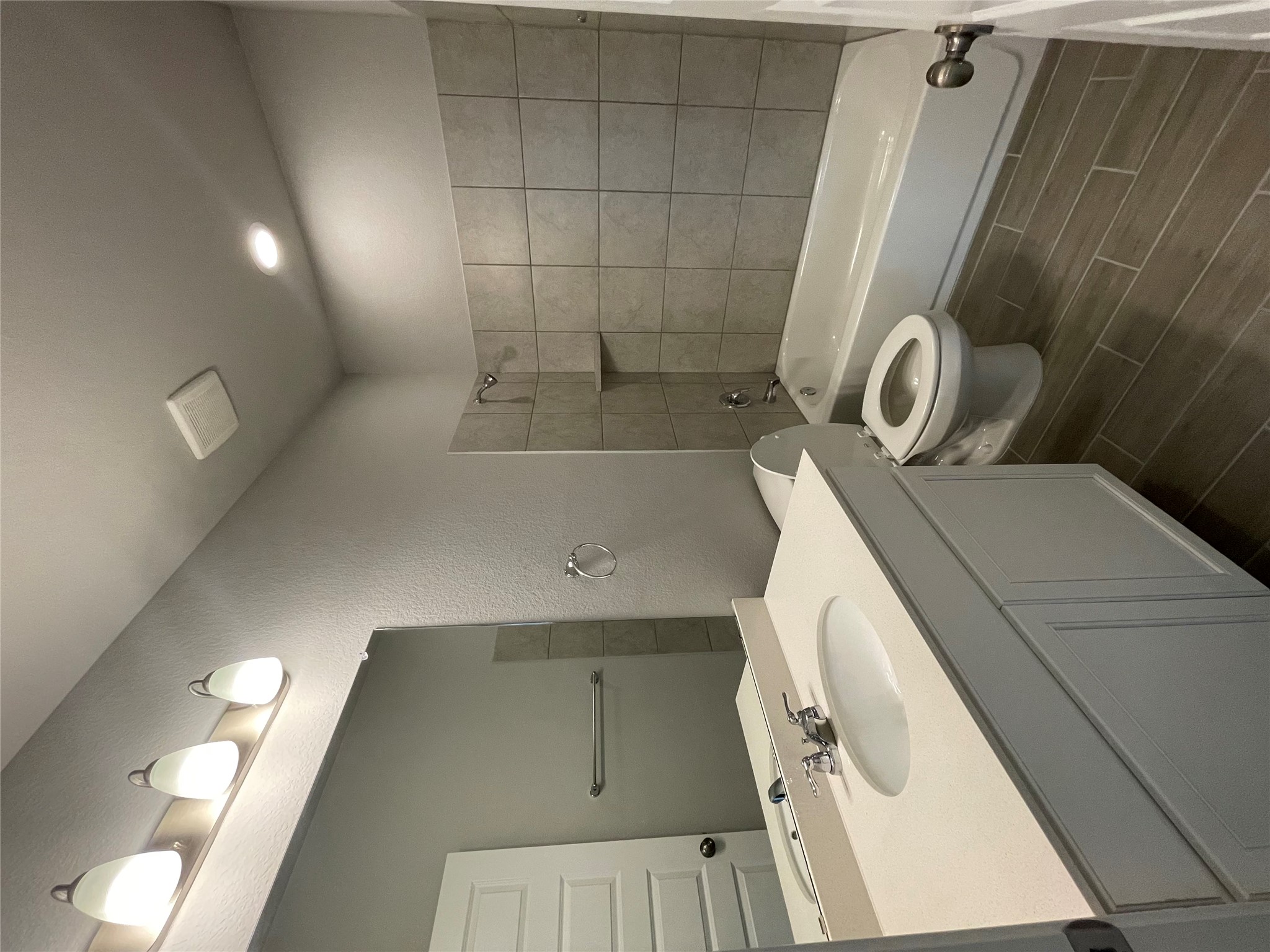 125 Unforgiven Lane Jarrell, TX 76537 - Photo 11 of 17 Bathroom featuring vanity, bathing tub / shower combination, wood finish floors, and a textured wall
