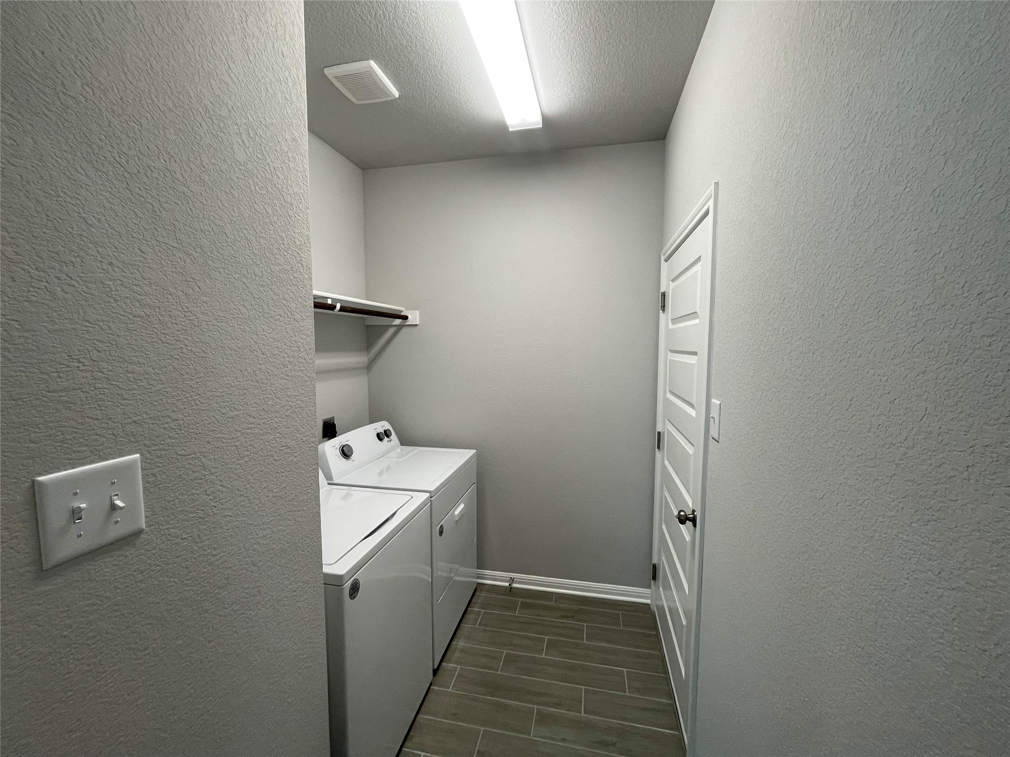 125 Unforgiven Lane Jarrell, TX 76537 - Photo 12 of 17 Laundry room featuring a textured wall, wood finish floors, washing machine and clothes dryer, and a textured ceiling