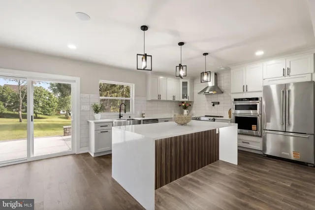 a kitchen with stainless steel appliances granite countertop a stove a sink dishwasher and a refrigerator with wooden floor