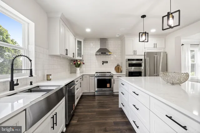 a kitchen with kitchen island granite countertop a sink cabinets stainless steel appliances and a counter top space