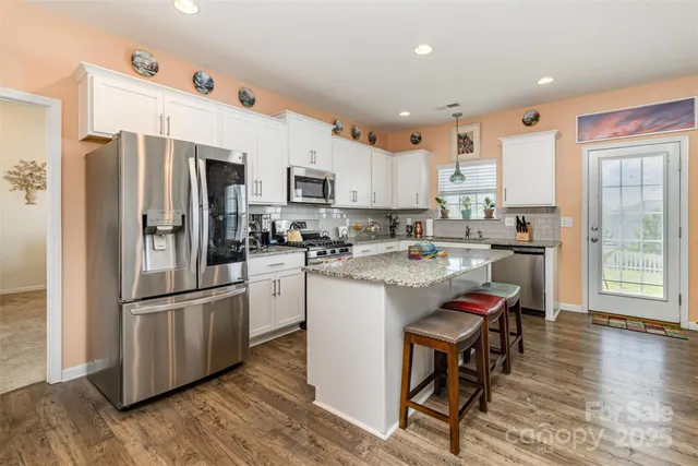 a kitchen with stainless steel appliances granite countertop a sink refrigerator and cabinets
