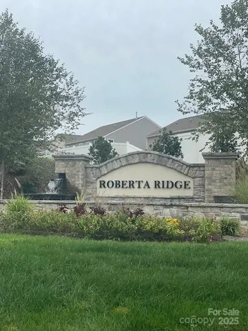 a view of a sign in front of a big yard with large trees
