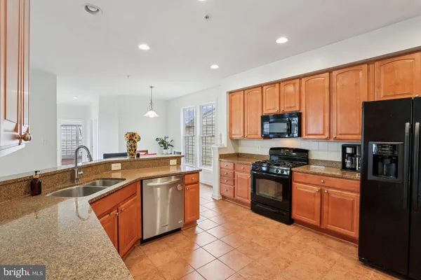 a large kitchen with stainless steel appliances granite countertop a stove a sink dishwasher and a refrigerator