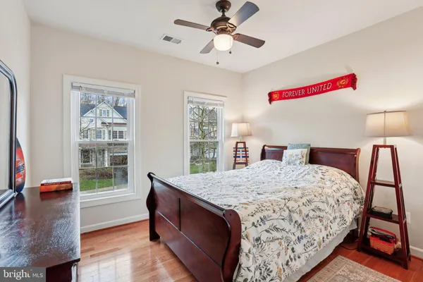 a bedroom with a bed and a dresser with wooden floor