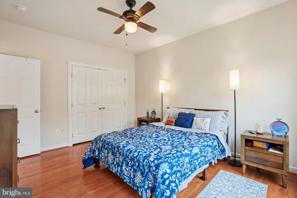 a bedroom with a bed and dresser with wooden floor