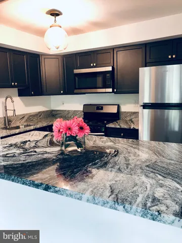 a kitchen with stainless steel appliances granite countertop a sink refrigerator and stove