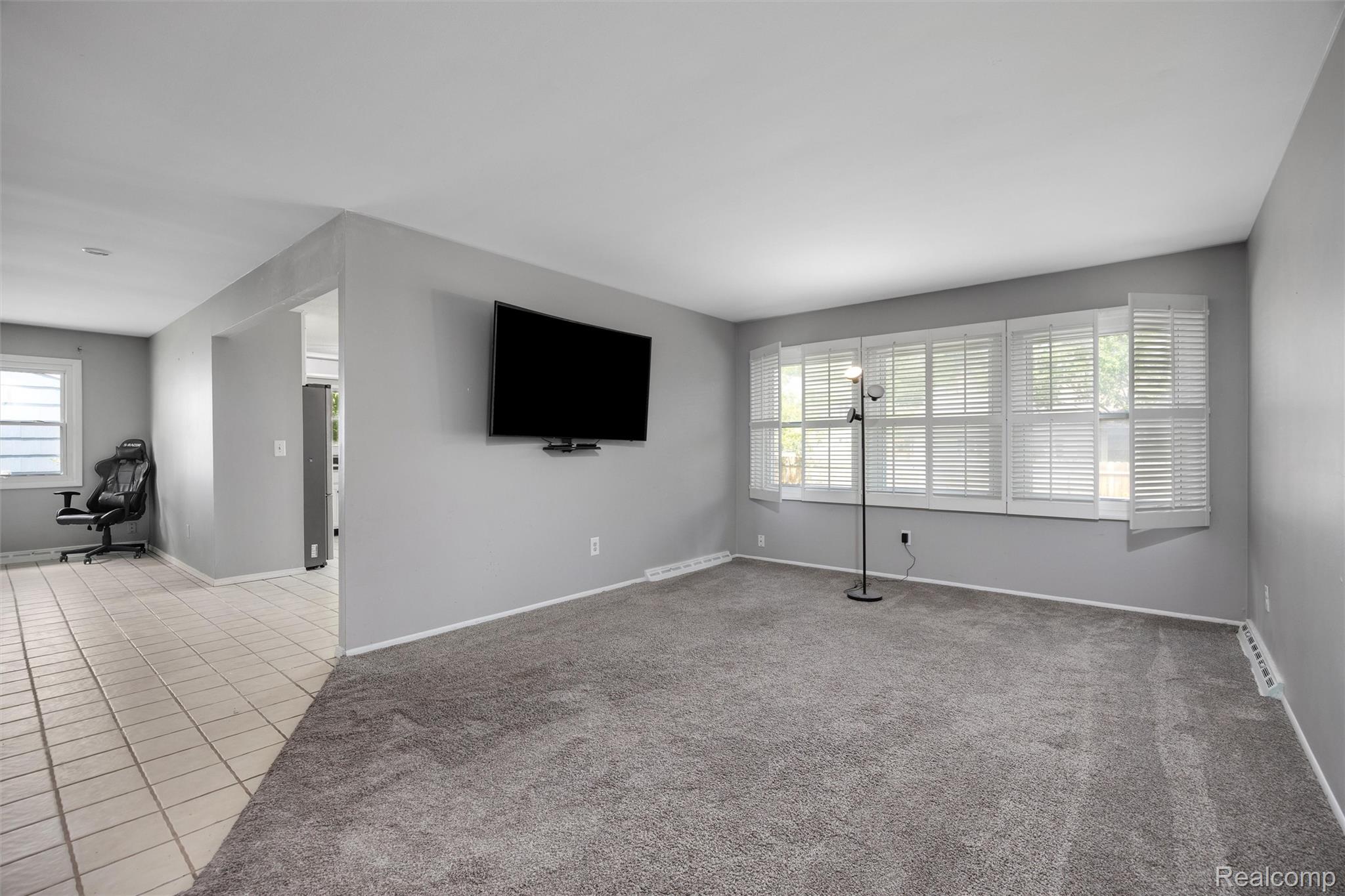 4942 Butler Drive Troy, MI 48085 - Photo 12 of 33 Living area featuring neutral-toned walls, gray carpeting, and a large window with white plantation shutters