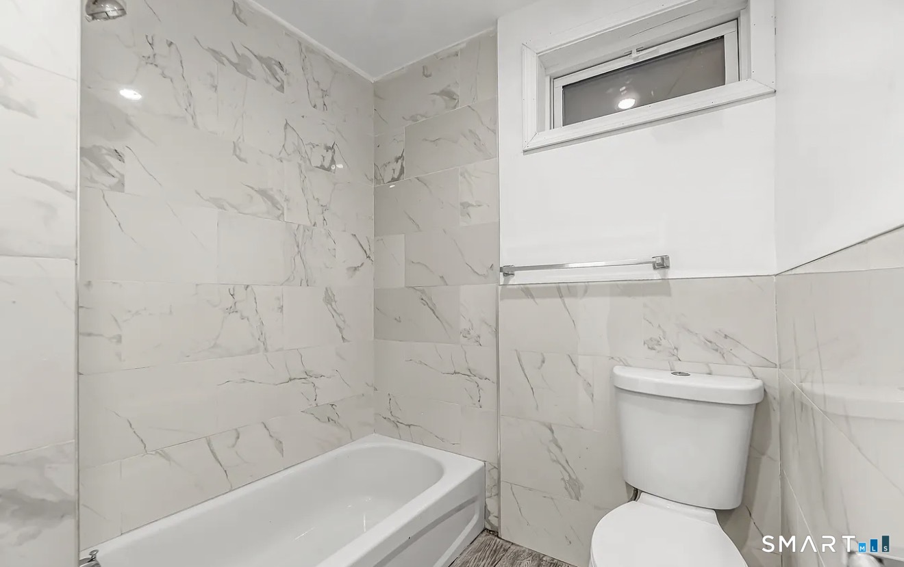 1220 Pembroke Street, Unit 3R Bridgeport, CT 06608 - Photo 11 of 12 a white toilet sitting next to a bath tub and a shower