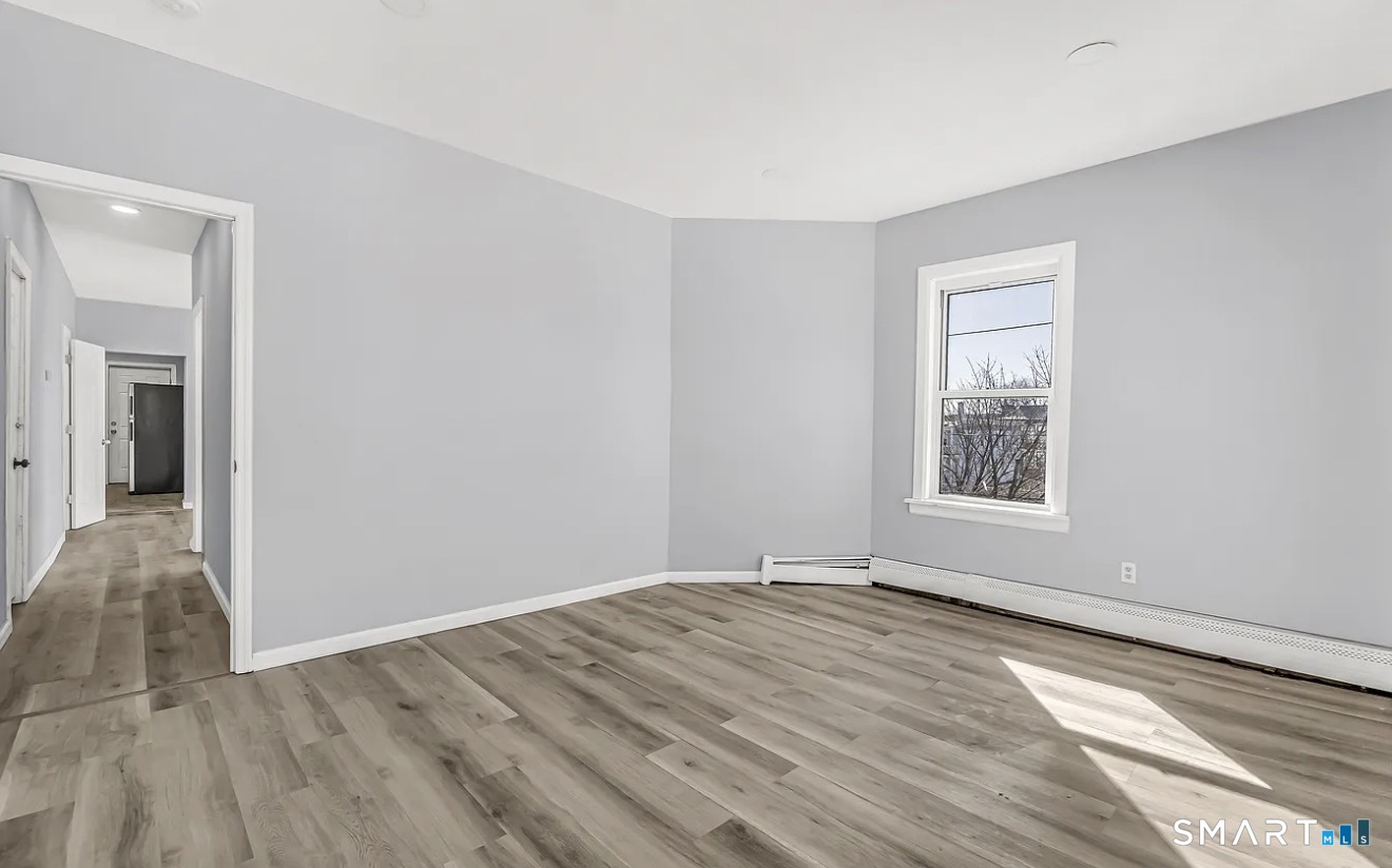 1220 Pembroke Street, Unit 3R Bridgeport, CT 06608 - Photo 7 of 12 a view of an empty room with wooden floor and a window