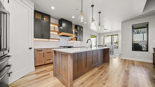 a kitchen with stainless steel appliances kitchen island granite countertop a stove a sink a refrigerator and a oven with wooden floor