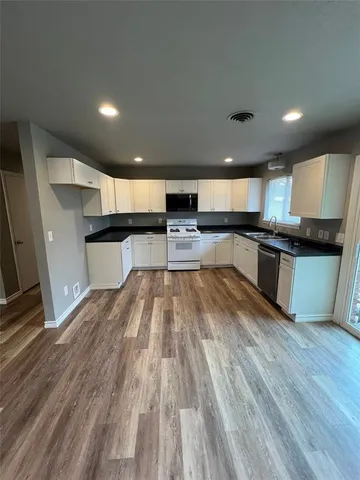 a large kitchen with stainless steel appliances and wooden floor