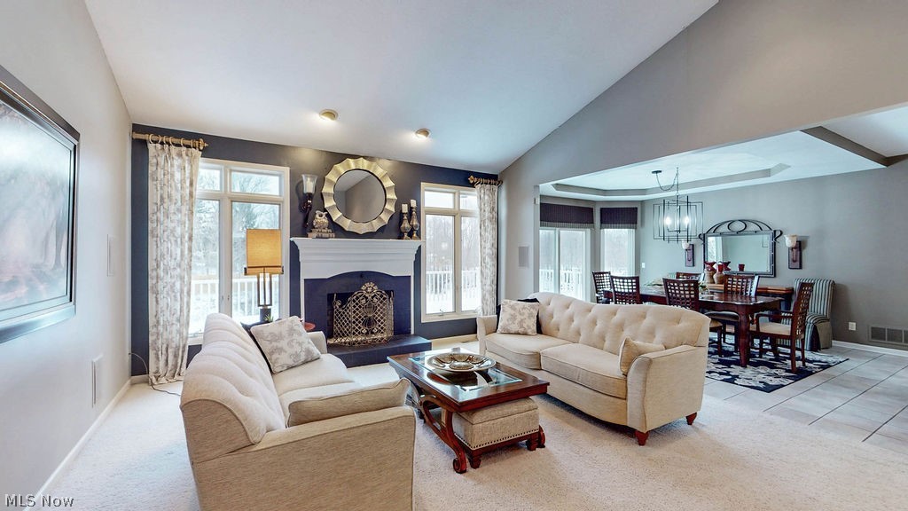 36845 Aberdeen Lane Solon, OH 44139 - Photo 7 of 24 Living room with vaulted ceiling, a fireplace with raised hearth, light carpet, and healthy amount of natural light