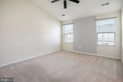 an empty room with windows and fan