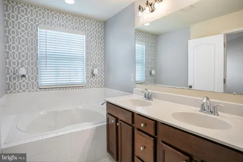a bathroom with a tub double sink window and mirror