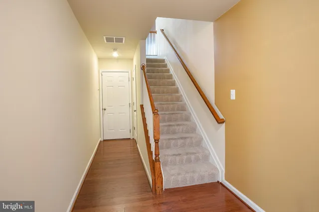 a view of a hallway with wooden floor and staircase