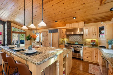 a kitchen with stainless steel appliances granite countertop a sink a stove and a wooden floors
