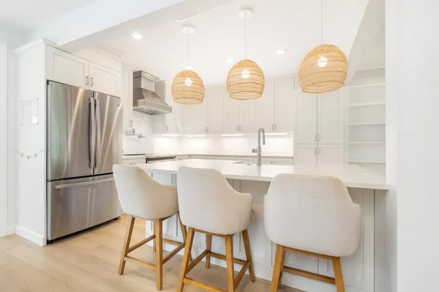 a kitchen with stainless steel appliances granite countertop a table chairs in it and wooden floors