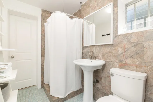 a bathroom with a sink a toilet and shower