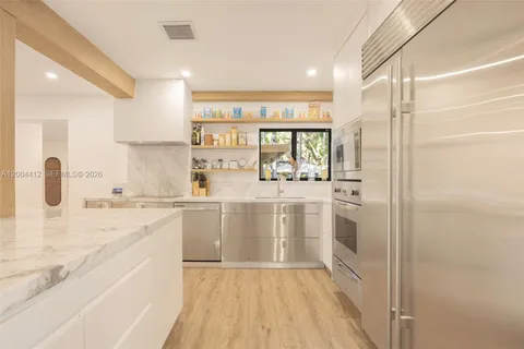a kitchen with stainless steel appliances a refrigerator and white cabinets