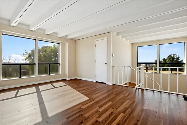 a view of a room with wooden floor and a floor to ceiling window