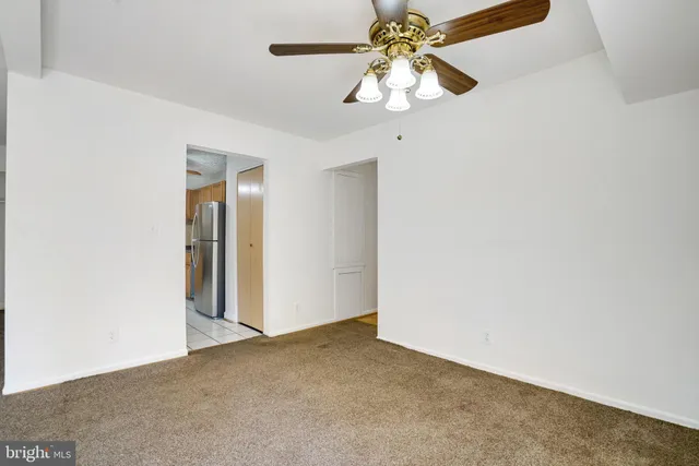 an empty room with a chandelier fan and closet