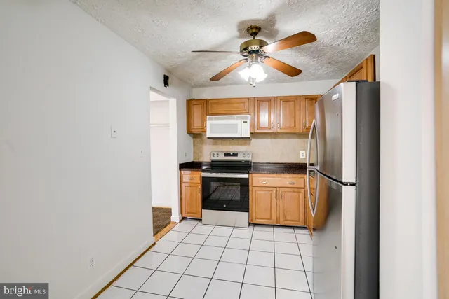 a kitchen with granite countertop a refrigerator and a stove top oven