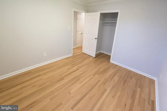 a view of an empty room with wooden floor and closet