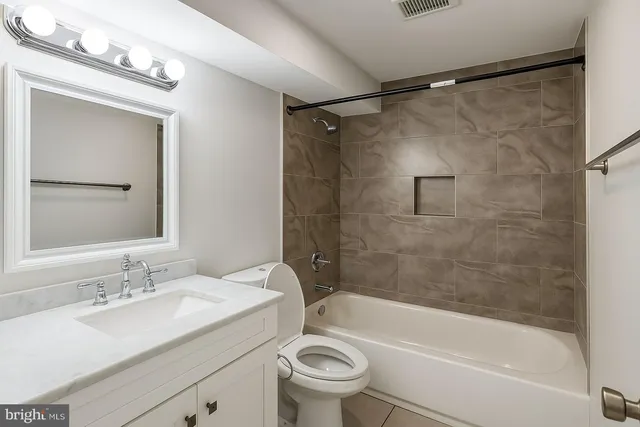a bathroom with a granite countertop sink a toilet and shower