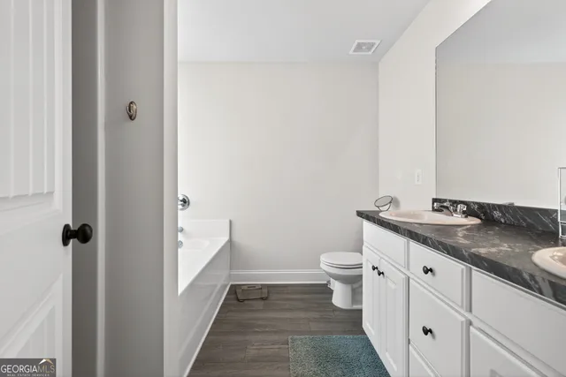 a en suite bathroom with a granite countertop sink and a mirror