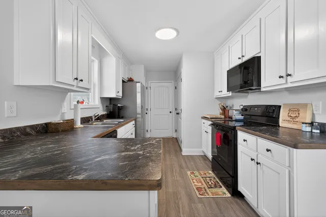 a kitchen with stainless steel appliances granite countertop a stove a sink dishwasher and a refrigerator with white cabinets