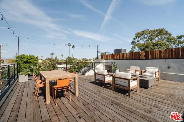 a view of a patio with table and chairs with wooden floor and fence
