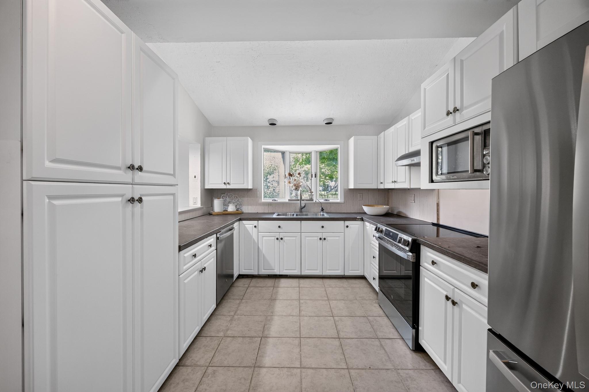 2 Terrace Road Suffern, NY 10901 - Photo 6 of 19 Kitchen featuring white cabinetry, dark countertops, a tile backsplash, and stainless steel appliances