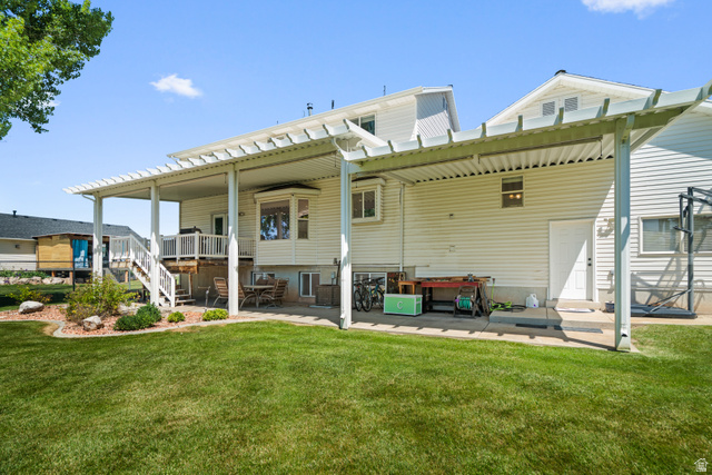 5727 South 3550th Street West Roy, UT 84067 - Photo 35 of 49 Expansive backyard featuring a manicured lawn, an extended patio with a pergola, and a multi-level deck with white railings