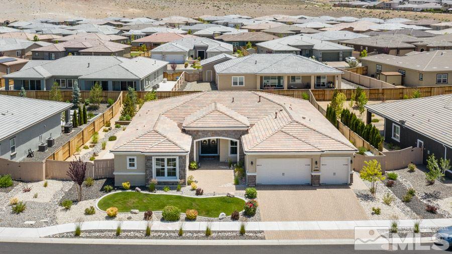 9850 Firefoot Lane Reno, NV 89521 - Photo 2 of 40 a view of a white house with a swimming pool and lawn chairs under an umbrella
