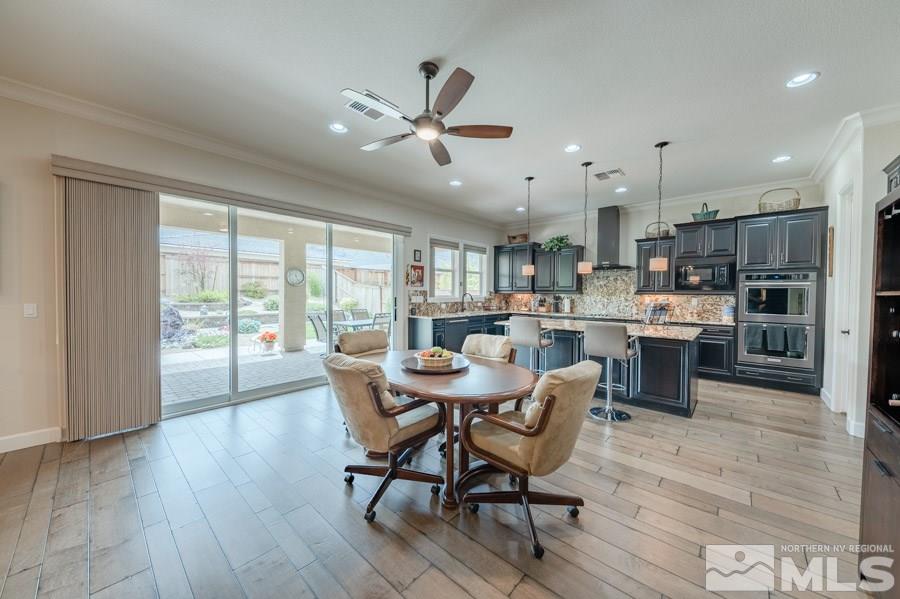 9850 Firefoot Lane Reno, NV 89521 - Photo 7 of 40 a dining room with kitchen island stainless steel appliances furniture a large window and wooden floor