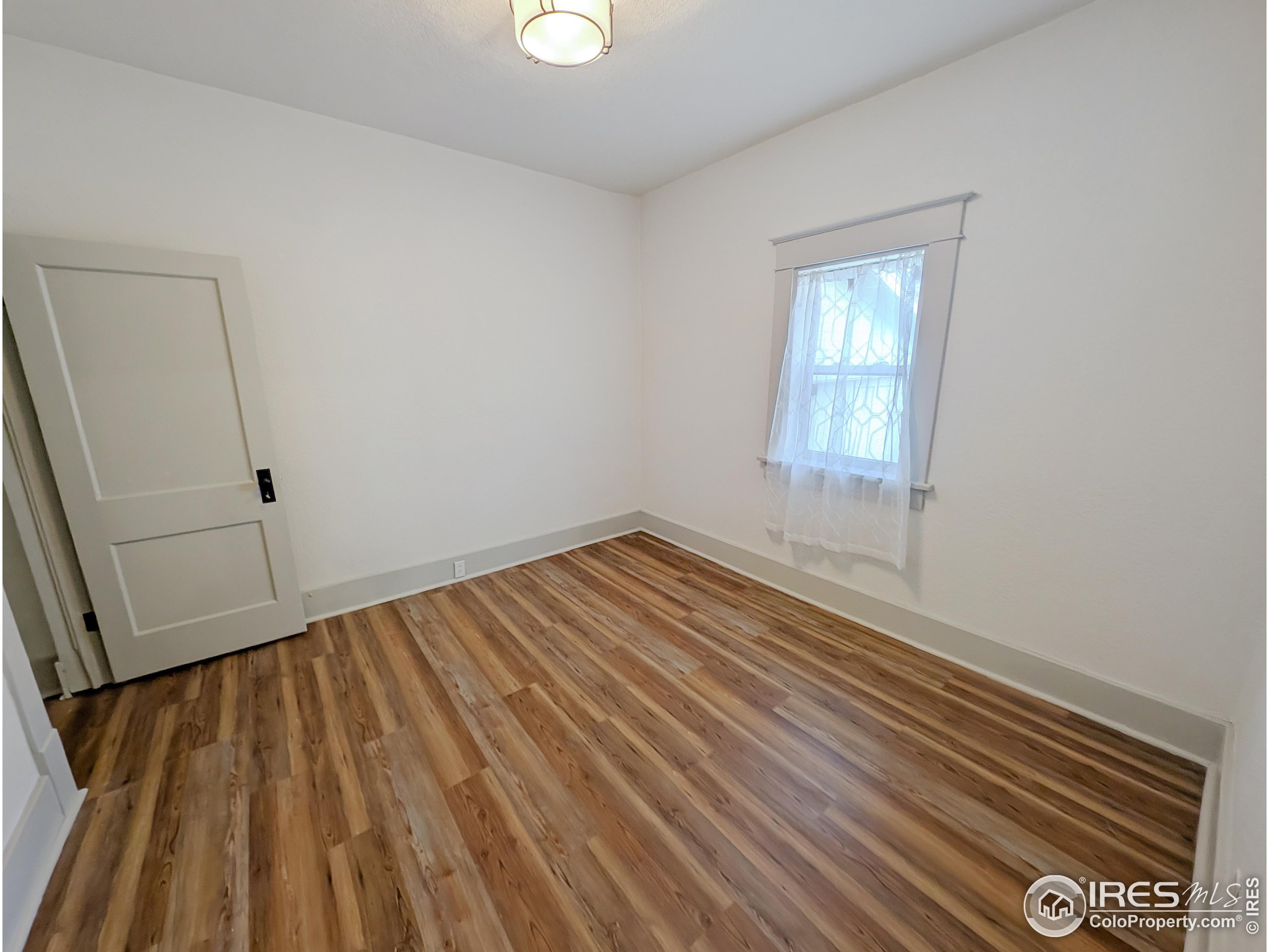 710 Carson Street Brush, CO 80723 - Photo 17 of 31 an empty room with wooden floor and windows