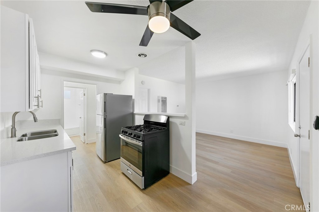 1242 Cedar Avenue Long Beach, CA 90813 - Photo 6 of 22 a kitchen with stainless steel appliances a refrigerator a sink dishwasher a stove and white countertops with wooden floor