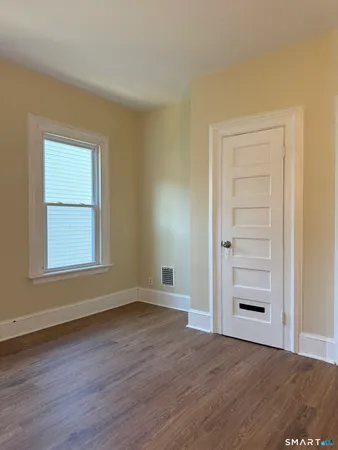 an empty room with wooden floor closet and windows
