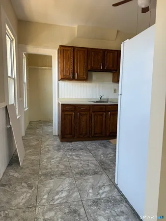 a view of kitchen with granite countertop cabinets and refrigerator