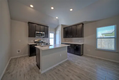 a large kitchen with stainless steel appliances granite countertop a stove a sink and a microwave