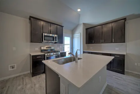 a kitchen with stainless steel appliances granite countertop a sink stove microwave and refrigerator