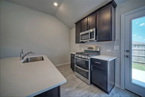 a kitchen with stainless steel appliances granite countertop a stove a sink and a microwave